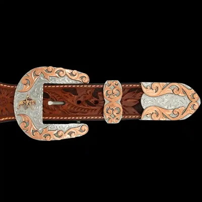 A custom western three piece belt buckle set featuring a cowboy figure and copper accents 